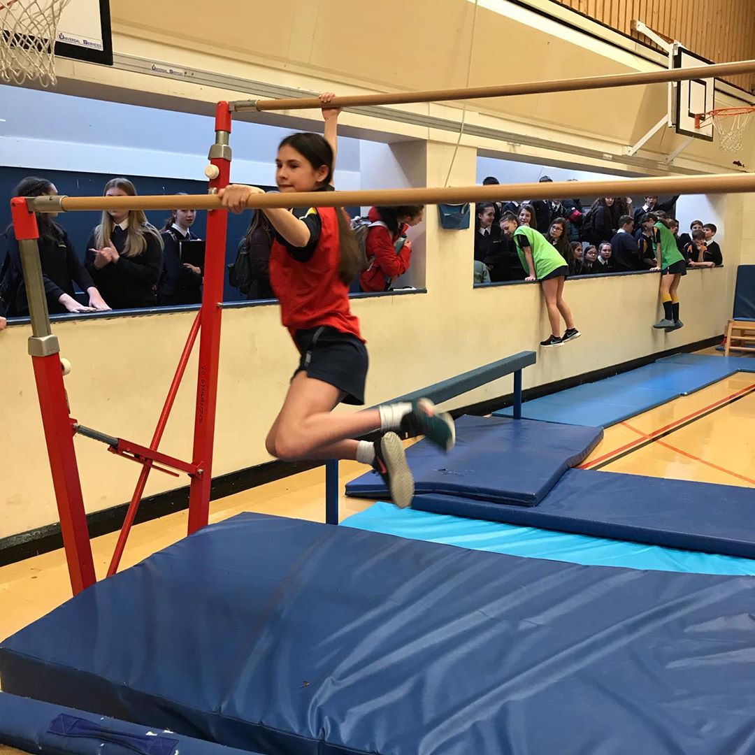 Girl leaps between parallel bars.