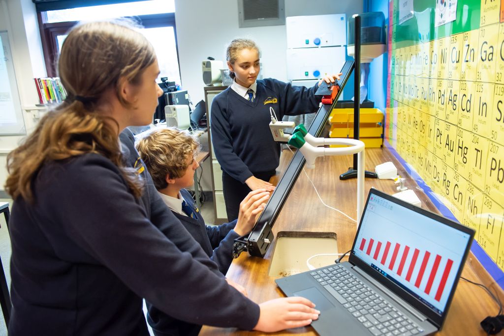 Students engaged in a physics experiment with a model car on a ramp