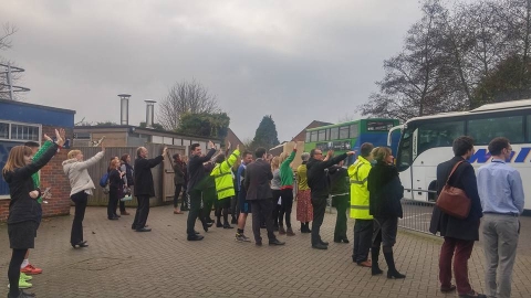 Teachers wave as the school buses depart